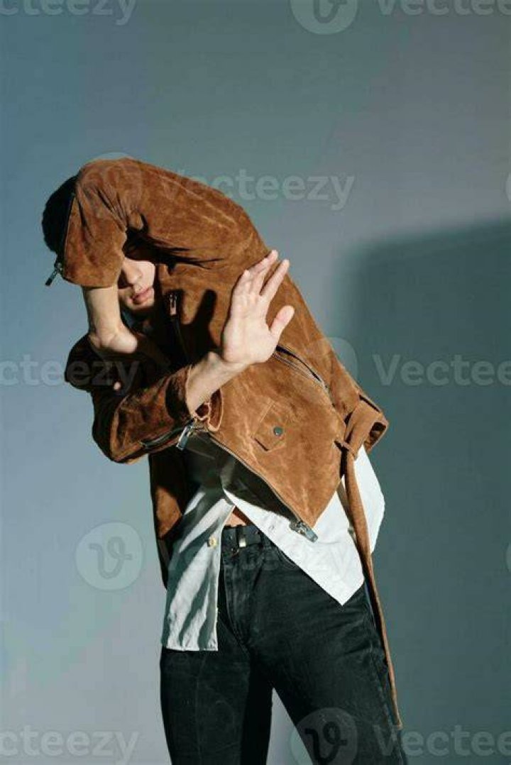 a man in a brown jacket is looking at the camera with a serious look on